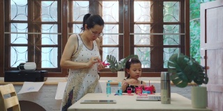 亚裔母亲在家工作，女儿在客厅玩