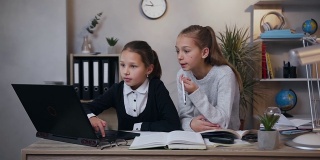 漂亮平衡不同年龄的女孩坐在一起，用电脑做作业