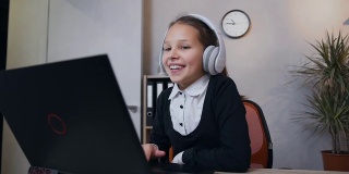 美丽快乐的少女在耳机里玩电脑上的视频游戏，并在胜利后举起她的手的慢动作