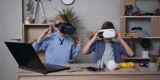 两个好看的青少年朋友-男孩玩电子游戏使用虚拟现实耳机和结束后击掌