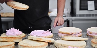 糖果师傅把奶油放在蛋糕上面。面包师用掼奶油糖霜使蛋糕光滑。高质量的全高清镜头