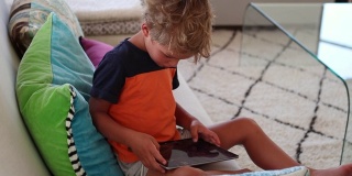 孩子在平板电脑上玩游戏。小男孩在家里使用电子设备