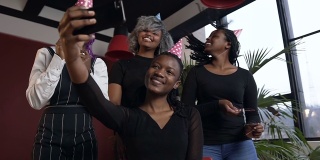 美丽的四个非洲女孩摆姿势在智能手机的相机，而使照片在生日聚会