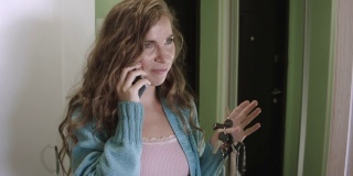 一个年轻女子在家里打电话的特写，拿着公寓的钥匙在她的手里。