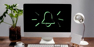 一个图标的铃闪烁在屏幕上的一个桌面电脑站在木桌上的动画