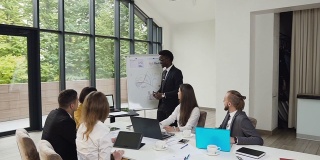 非裔美国人在白板上制作图表，在公司培训办公室为业务同事开会头脑风暴