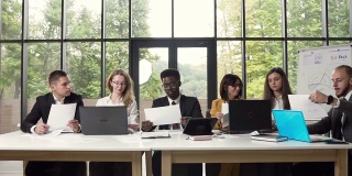年轻的多民族员工坐在现代办公室的办公桌后处理文件和技术。在大公司处理文件的商人