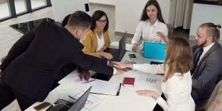 成功的商业团队与他们的合作伙伴团结一致，坐在办公室的会议桌前。全神贯注于工作