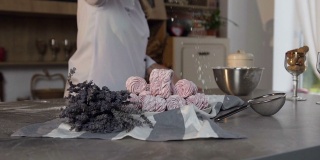 在时尚的厨房里，糖果商在盘子里的粉色棉花糖上撒糖粉