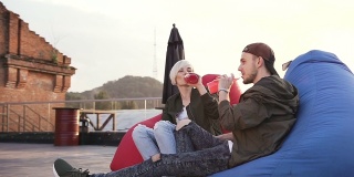 年轻的男孩和女孩坐在阳台咖啡馆的多色扶手椅上喝能量饮料。朋友们一边喝着鸡尾酒，一边聊天，尽情地送出五份礼物
