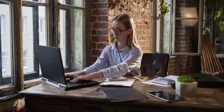 美丽的商务女孩工作与文件和笔记本电脑-工作时间在现代办公室工作的概念。一个年轻白种女人正在办公室处理工作场所的财务文件