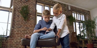 漂亮的白人孩子在平板电脑上玩在线游戏。两个十几岁的兄弟在电脑平板设备上玩游戏。孩子们在网上学习英语