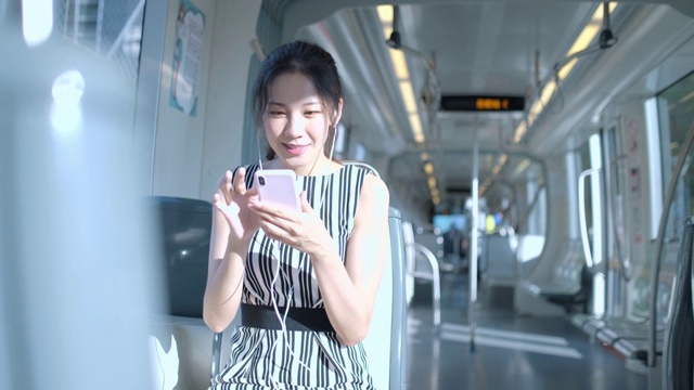 年轻女子在乘坐地铁上下班时使用手机