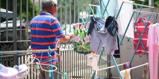 亚洲华人老人收集挂在前院清洗后的衣服