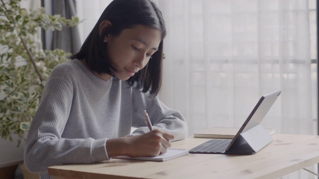 在家教育。亚洲儿童坐在客厅里做作业和使用数字平板电脑，在家在线学习的概念