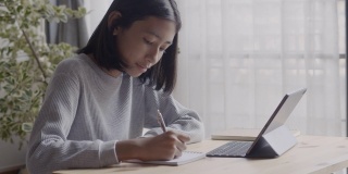 在家教育。亚洲儿童坐在客厅里做作业和使用数字平板电脑，在家在线学习的概念