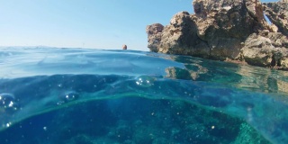 克罗地亚亚得里亚海，一名身穿比基尼的年轻女子从岩石上跳入阳光灿烂的海洋