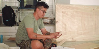 有纹身的Asain Man在新厨房里组装洗水槽柜。