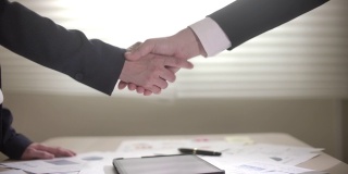 在数字平板电脑上签署合同和握手时，女商人和商人的慢动作手