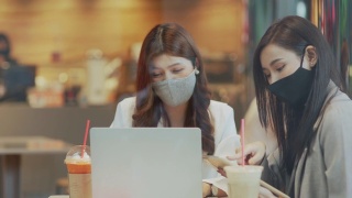 两个亚洲女性在商务会议上一起使用笔记本电脑进行讨论视频素材模板下载