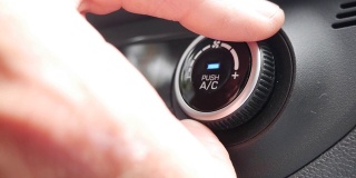 特写，按按钮打开汽车里的空调。男子的手转动按钮，调整车内的舒适度