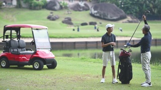亚洲华人成年人从高尔夫球袋中挑选高尔夫球棒，并在高尔夫球场开球点指导教儿子视频素材模板下载