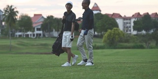 在马六甲高尔夫球场上，一名亚洲华人老人与他的儿子在比赛结束后愉快地散步和交谈