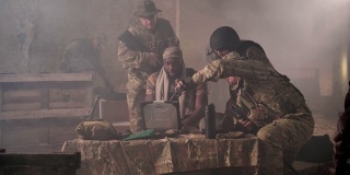 黑皮肤的士兵在烟雾弥漫的大楼里摆弄笔记本电脑