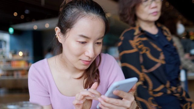 一个年轻的亚洲女人在咖啡店打电话