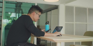 亚洲人使用智能手机和电脑在家工作。