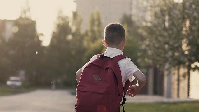 跟踪，慢动作:一个男生放学后跑回家。他身后是一个书包。