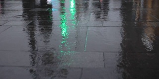 行人的脚步在雨后潮湿的路面上折射出城市的影子
