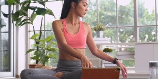 亚洲女性在家通过平板电脑跟随在线教程锻炼