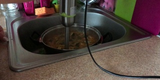烹饪南瓜鱼子酱。一位妇女用搅拌机在炖锅里磨食材。