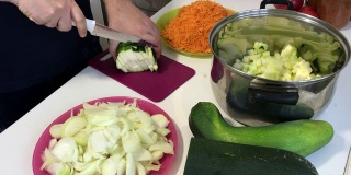 一个男人在磨蔬菜骨髓。附近的蔬菜，烹饪南瓜鱼子酱。桌上放着西葫芦，胡萝卜，洋葱和西红柿