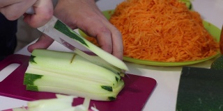 一个男人在磨蔬菜骨髓。附近的蔬菜，烹饪南瓜鱼子酱。桌上放着西葫芦，胡萝卜，洋葱和西红柿。特写镜头。