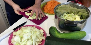 一个男人在磨蔬菜骨髓。附近的蔬菜，烹饪南瓜鱼子酱。桌上放着西葫芦，胡萝卜，洋葱和西红柿。