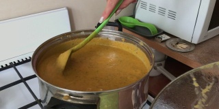 烹饪南瓜鱼子酱。一位妇女正在平底锅里用煤气搅拌南瓜鱼子酱。