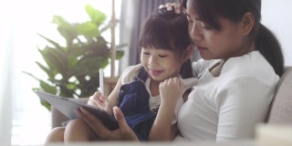 孩子在线学习的数字平板电脑与她的母亲在家里