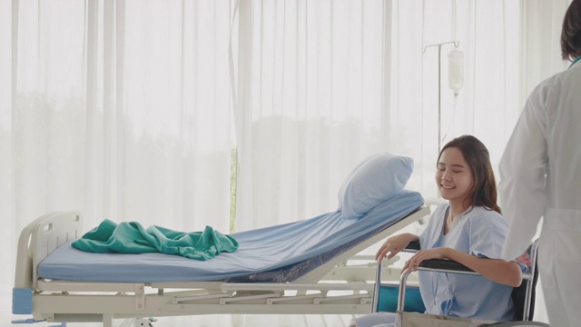 亚洲女医生在医院治疗和照顾病人。使用轮椅转送门诊病人。妇女们很高兴他们被照顾的医生。医疗保健医学概念