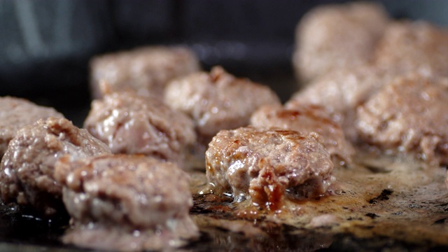 Meatballs are fried in oil in a frying pan with air bubbles.
