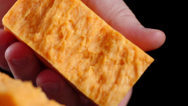 男人的手把切达干酪掰成两半。