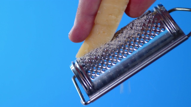 男性用手在一个小刨丝器上擦帕尔马干酪。