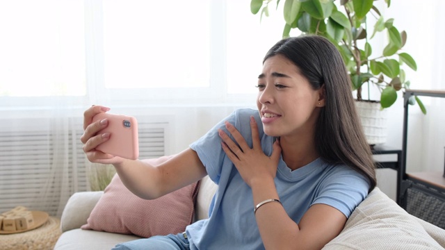 惊奇的女人在家里用手机视频聊天