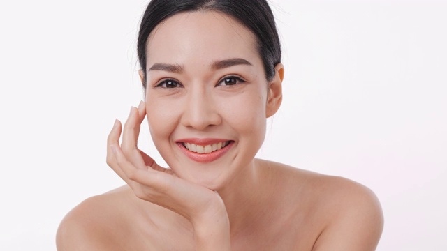 微笑的亚洲妇女肖像应用面霜与白色的背景。