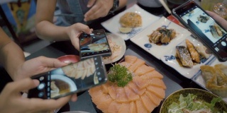 亚洲女性用智能手机拍下日本美食，在社交媒体上分享乐趣和幸福。