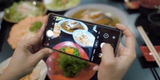 亚洲女性用智能手机拍下日本美食，在社交媒体上分享乐趣和幸福。
