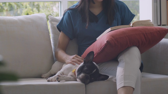 一个女人一边看书，一边抚摸着她的狗。
