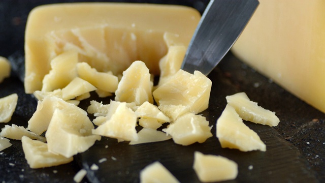 用刀切开一片帕尔马干酪，慢慢旋转。