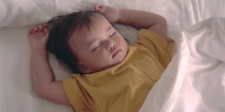 亚洲女婴在舒适的白色床上熟睡